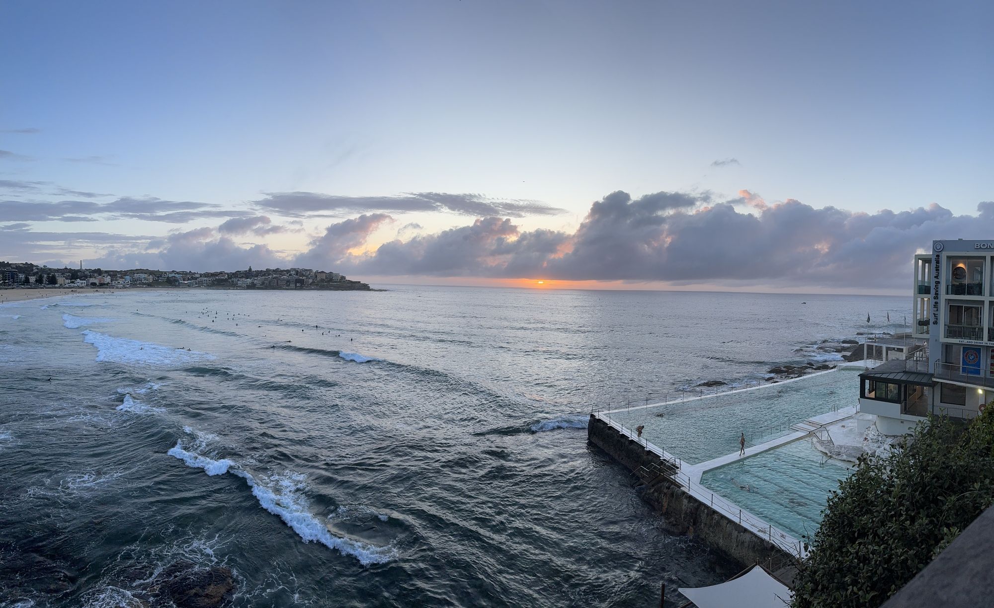 Dawn light over an ocean pool carved into the rocks, waves breaking beyond, Sydney.