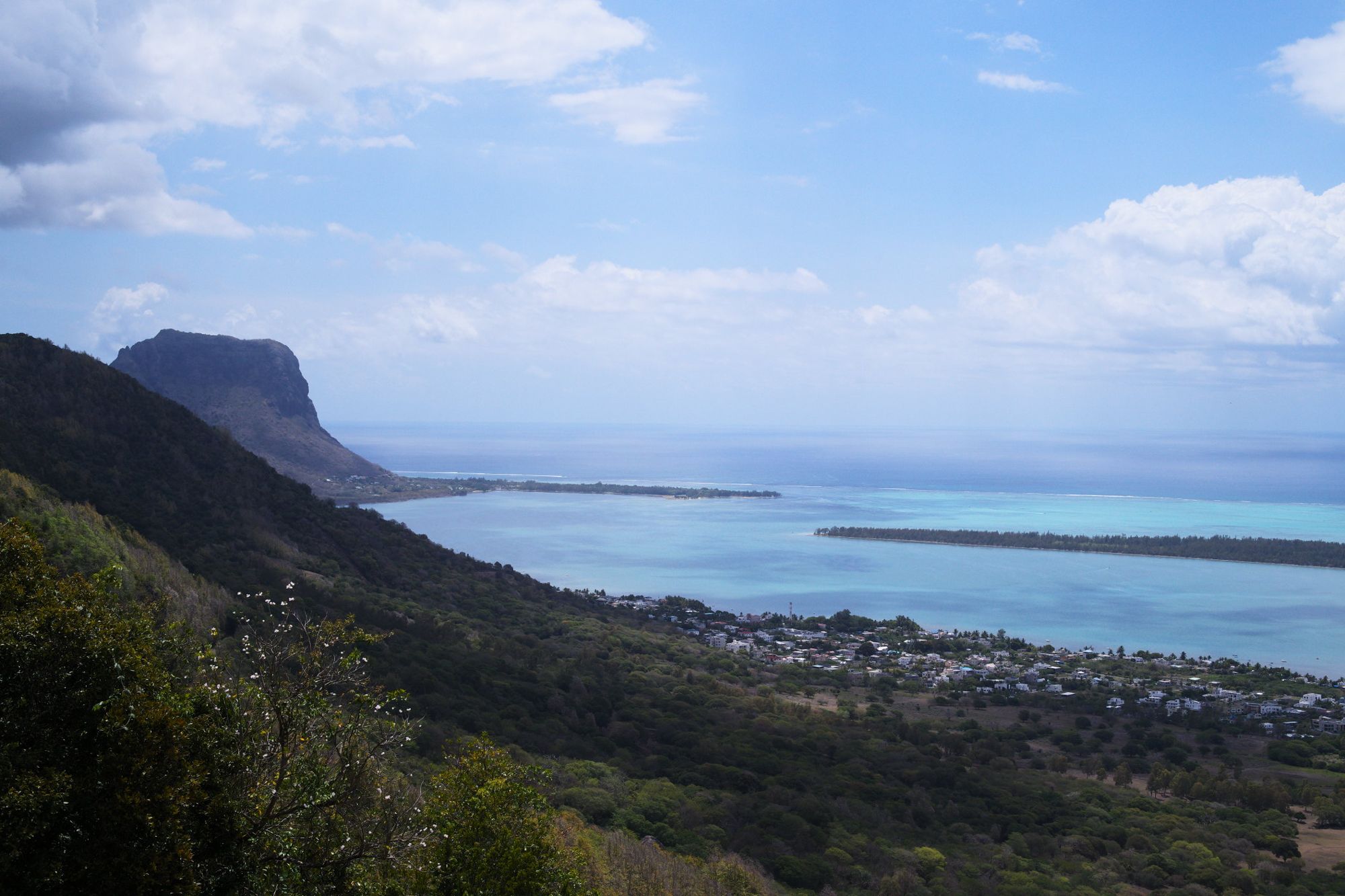 View over the lagoon and coastline toward Le Morne Brabant under a wide sky, Mauritius.